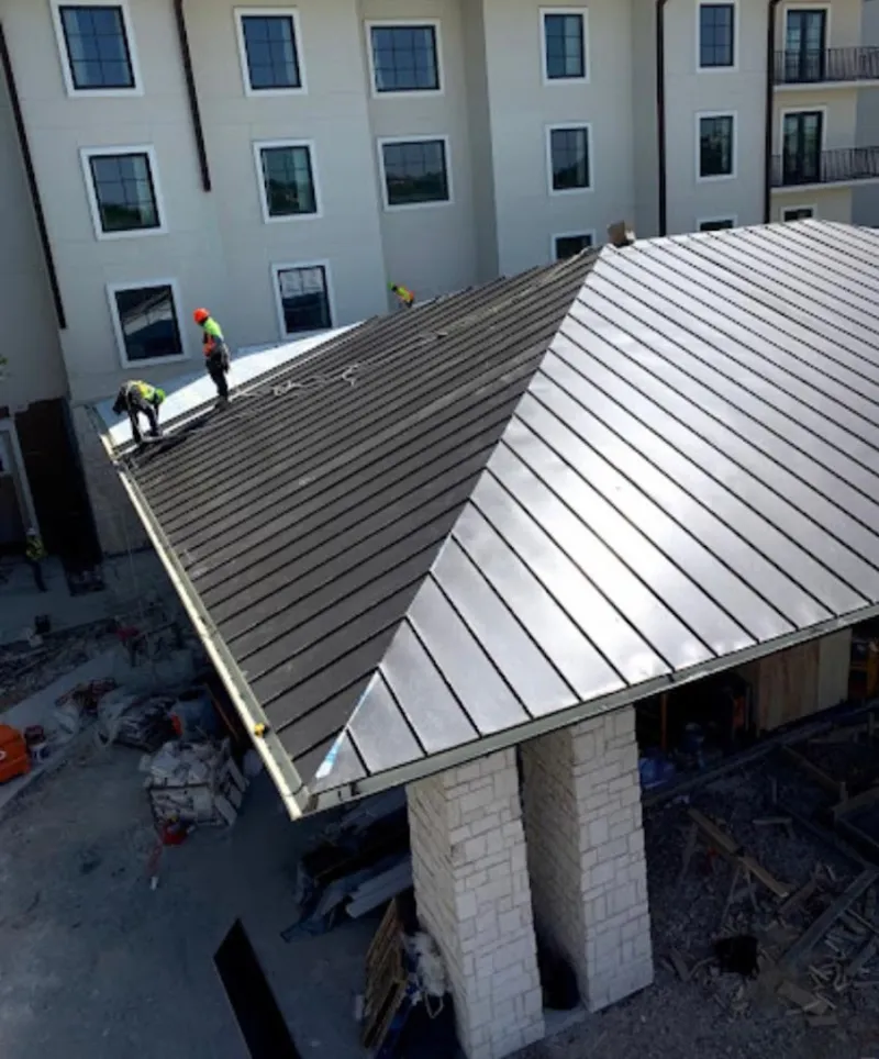 Crew installing standing seam metal roof panels on a commercial project in Moody